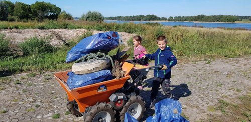 Zwei Kinder schieben eine Schubkarre mit Plastikmüll aus dem Rhein