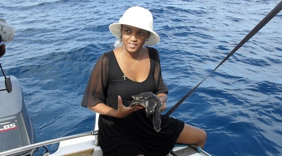 Frau auf Boot mit junger Karettschildkröte