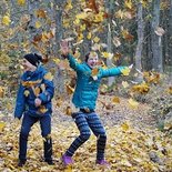 Jugendliche werfen Herbstblätter hoch