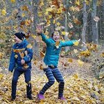 Zwei Kinder Werfen Blätter In Die Luft.