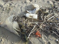 Plastikflasche und anderer Plastikmüll am Sandstrand